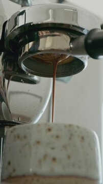 4K Liquid espresso flowing through naked portafilter, coffee making process.