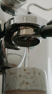 4K Liquid espresso flowing through naked portafilter, coffee making process.