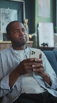 Content person browsing and laughing comfortably, Casual man engaged with social feed in cozy home environment