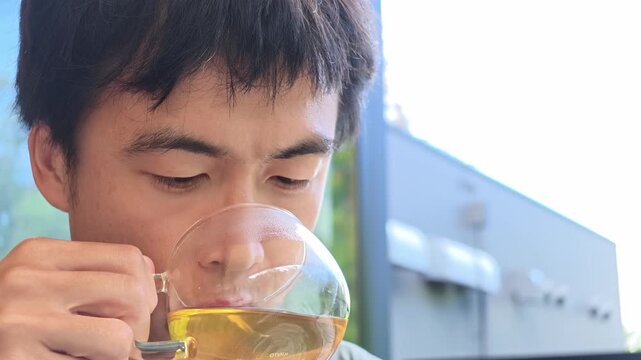 Man sips tea with quiet contemplation. Soft light frames his thoughtful expression. Scene suggests calm, everyday ritual. Ideal for tranquil moments or wellness themes