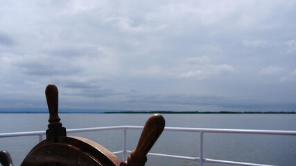 The ship's helm over calm waters. © Elena