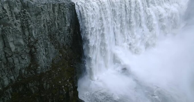 Slow motion aerial camera pans upward revealing Dettifoss Waterfall on the Jokulsa a Fjollum in Jokulsargljufur Canyon, Vatnajokull National Park, Northeast Iceland, exposing cascading glacial water