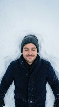 Young man resting peacefully on fresh snow wearing warm winter clothing