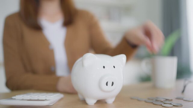 Young Asian woman putting coin in piggy bank. Save money and financial investment