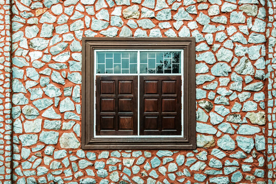 Vintage building facade with stone wall and wooden windows. Exterior view of vintage building featuring beautifully textured stone masonry wall. traditional wooden panel windows with white frames.