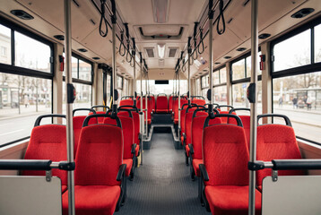 Fototapeta premium Empty interior of a modern urban public bus with bright red seats