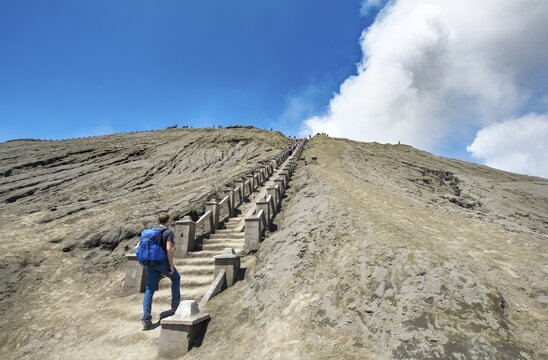 Young man on the stairs to the crater rim of the smoking volcano Gunung Bromo, National Park Bromo-Tengger-Semeru, Java, Indonesia