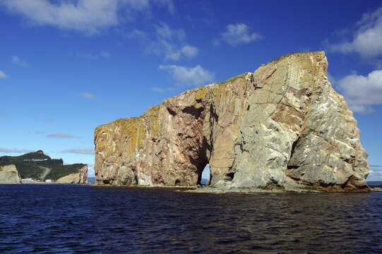 Large rocky cliffs in the sea under a blue sunny sky, Rock of Perce, Perce, St. Lawrence River, Gaspesie, Quebec, Canada