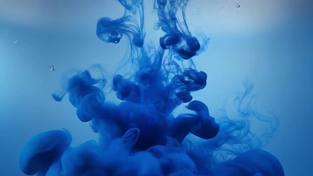 Blue ink swirling and diffusing underwater with bubbles
