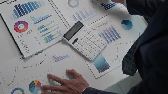 Businessman analyzing financial report using calculator