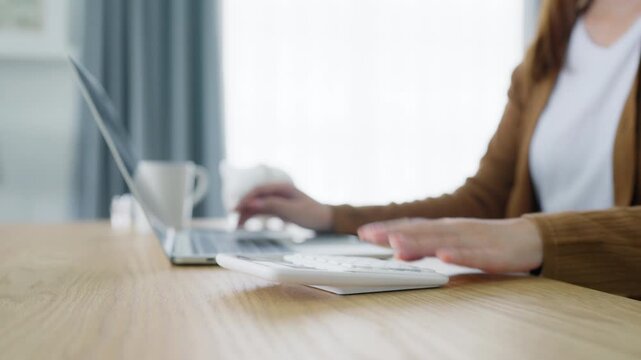 Beautiful young Asian woman working with laptop computer in home kitchen. Work at home