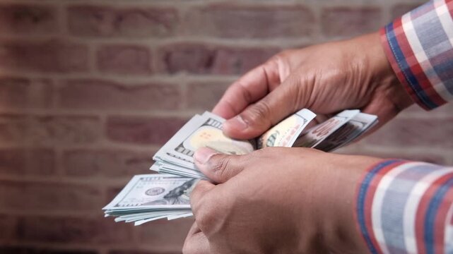 Man's hands counting a stack of one hundred dollar bills in motion