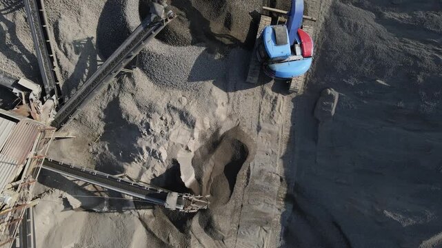 Aerial Scenery of Blue Excavator Working Near Stone Crusher and Stockpiling Area in Industrial Mine Site