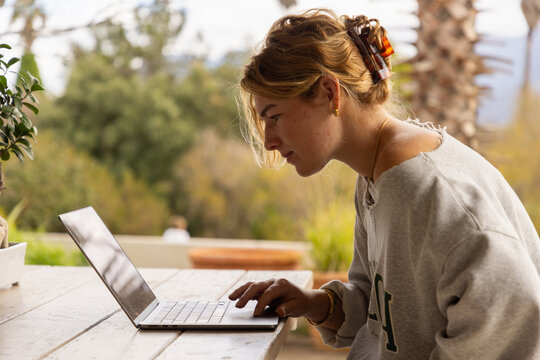 young woman using laptop computer on outdoor patio