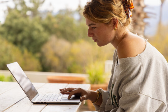 young woman using laptop computer on outdoor patio