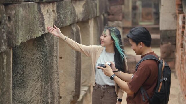 Young Asian Couple Exploring Ancient Stone Temple with Camera, Cultural Heritage Travel Experience