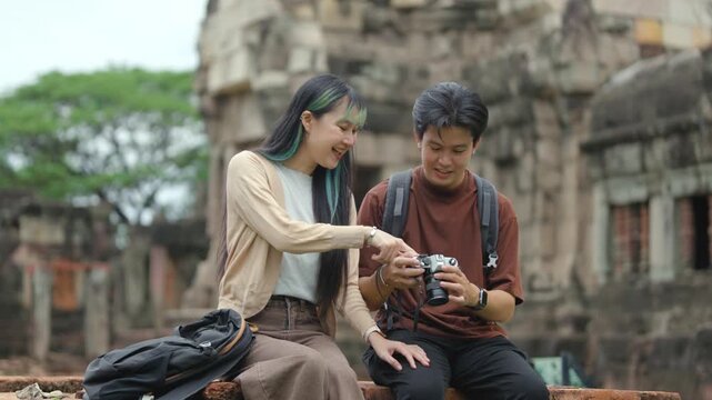 Young Asian Couple Reviewing Travel Photos Together at Ancient Temple Heritage Site