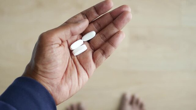 Close up of hand holding three white pills for medical treatment motion