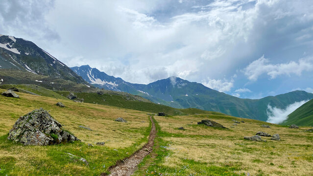 Alpine trail leads across open highland meadows on the Roshka to Juta route in Georgia, supporting hiking maps