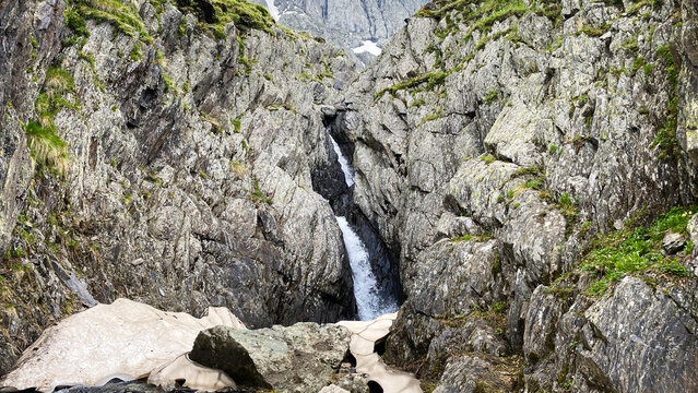 Mountain meltwater cascades through a narrow rocky gorge below Chaukhi in Georgia, documenting seasonal snowmelt