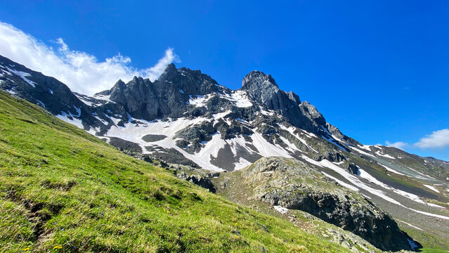 Chaukhi Mountain rises above the alpine pass in Georgia with jagged rock towers, snowfields, and grassy slopes