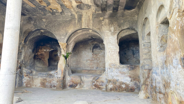 Ancient rock-cut hall inside Uplistsikhe features carved arches, columns, niches, and weathered stone surfaces in Georgia