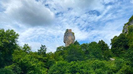 Katskhi Pillar stands isolated above a forest in a distant wide view, with the hilltop church framed by layered clouds in Imereti © chekart