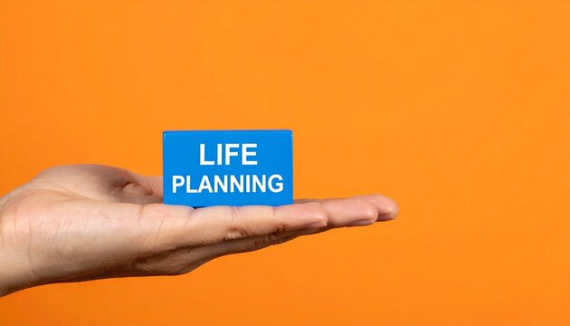 Hand holding LIFE PLANNING block against bright orange background