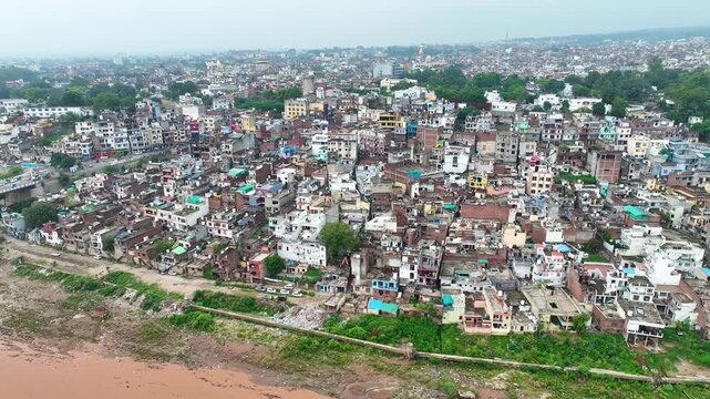 Aerial drone of vulnerable riverbank settlements, Jammu floods and rainy season Tawi river erosion risk establishing shot