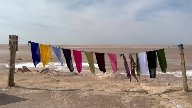 Colorful scarves hang on a line by the dry salt lake of Chott el Djerid in Tunisia.