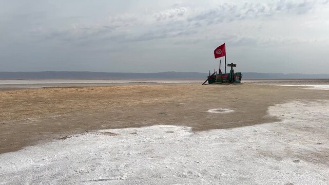 Pan left Ship-shaped wooden platform with a Tunisian flag at Chott el Djerid Desert Lake in Tunisia.