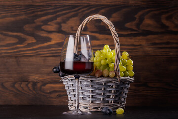 Obraz premium Red wine glass and basket of fresh grapes