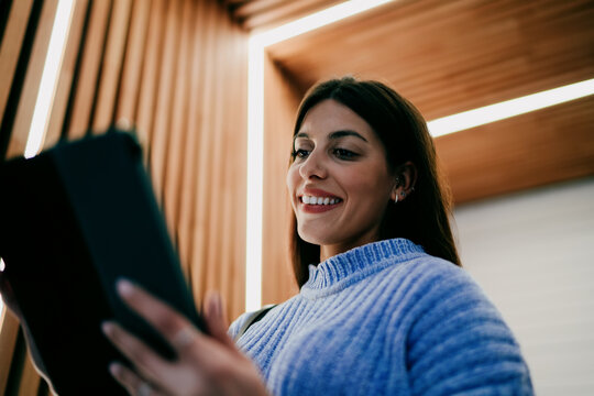 smiling brunette woman looking at tablet screen. Digital banking, mobile payment, online shopping or social media interaction. Tech savvy female user enjoying high speed internet connection.