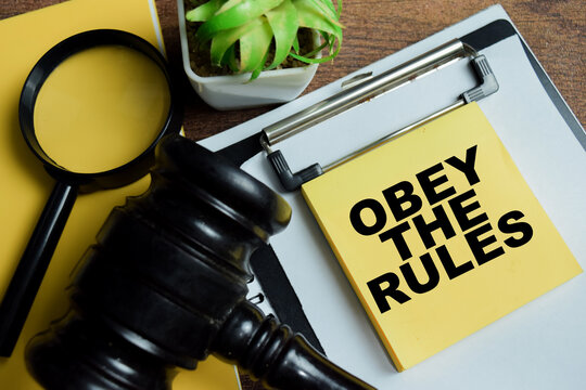 Concept of obey the rules write on sticky notes isolated on Wooden Table.