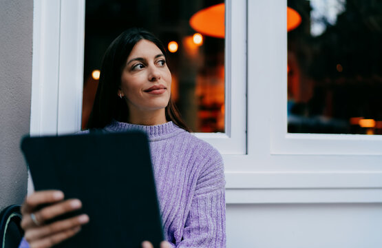 Successful woman using tablet device in modern office corridor with wooden walls. Digital nomad browsing online, creative designer working remotely, modern IT business concept, wireless connection.