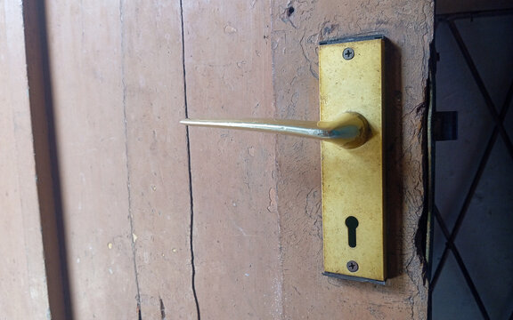 Vintage Brass Door Handle with Keyhole on an Aged Wooden Door