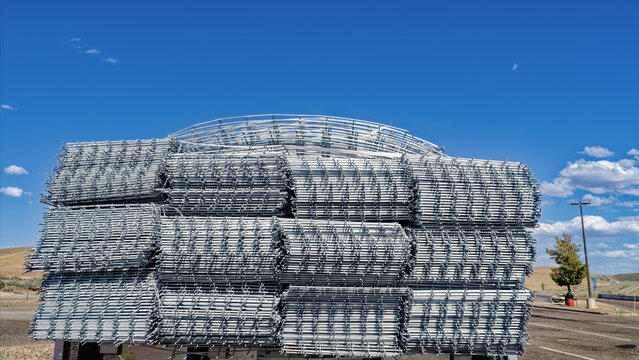Rolls of galvanized wire fencing stacked on a flatbed semi trailer parked in a rest stop on Interstate 80