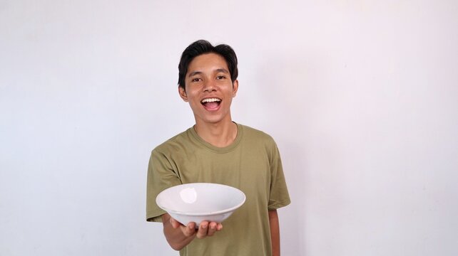 excited young asian man holding and showing empty bowl