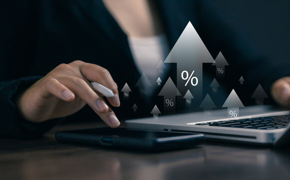 Businesswoman using digital devices with percentage icons and rising arrows, representing interest rates, financial growth, investment performance, banking, and economic trends.