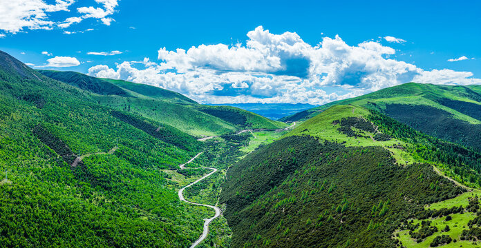Aerial view of a scenic winding road passing through a lush green mountain valley in Sichuan, China