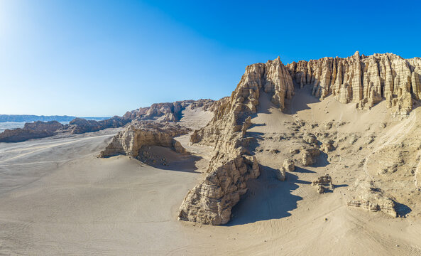 Aerial view of towering eroded clay cliffs in a yardang desert landscape under a clear blue sky, Dahaidao, Xinjiang, China
