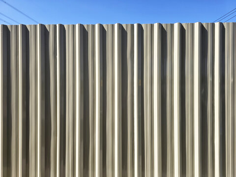 Industrial Corrugated Metal Wall Texture with Cinematic Light and Blue Sky Background.
