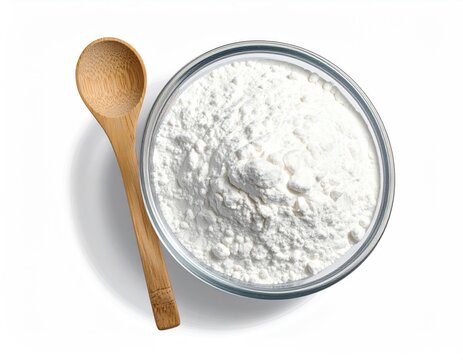 Overhead view of a glass bowl filled with white powder beside a wooden spoon