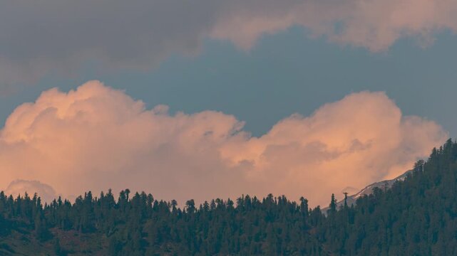 4K Time lapse shot of orange clouds above the Pine tree forest on a Himalayan mountain peak seen during the monsoon season at Manali in Himachal Pradesh, India. Scenic natural background.