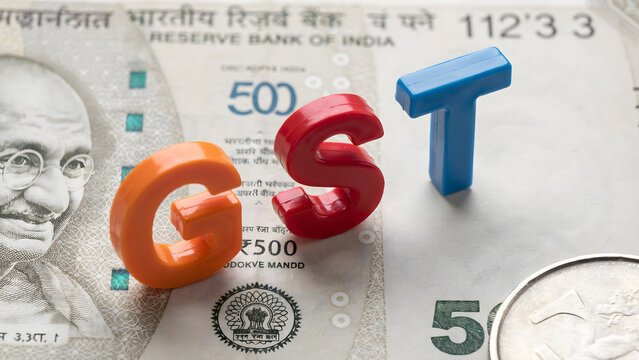 Colorful plastic letters forming a tax abbreviation on Indian currency