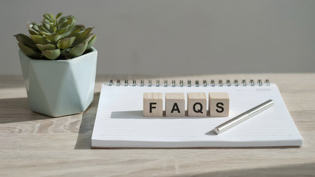 Wooden blocks spelling faqs on a spiral notebook with a succulent plant