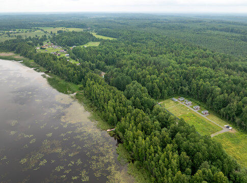 Aerial view of a small holiday resort and sub-divided land plots by a quiet forest lake on an overcast summer day in Karelia, Russia
