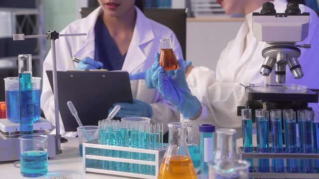 Two scientists conducting a chemistry experiment with test tubes, laptop and microscope in a modern laboratory