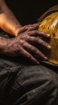 Extreme macro shot of soot covered hands resting on yellow fire helmet, firefighter dedication and frontline duty concept