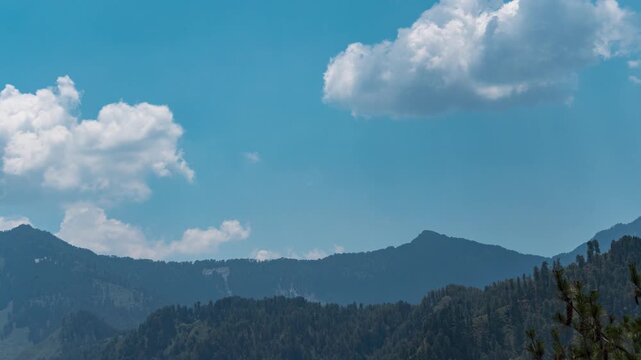 4K Time lapse shot of clouds rolling above Himalayan mountain peaks during the summer season as seen from Peej village near Kullu in Himachal Pradesh, India. Scenic natural background with copy space